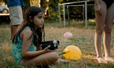 A young girl sits on the ground at a garden party