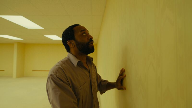 A man looks in horror at a blank wall where a door has disappeared.