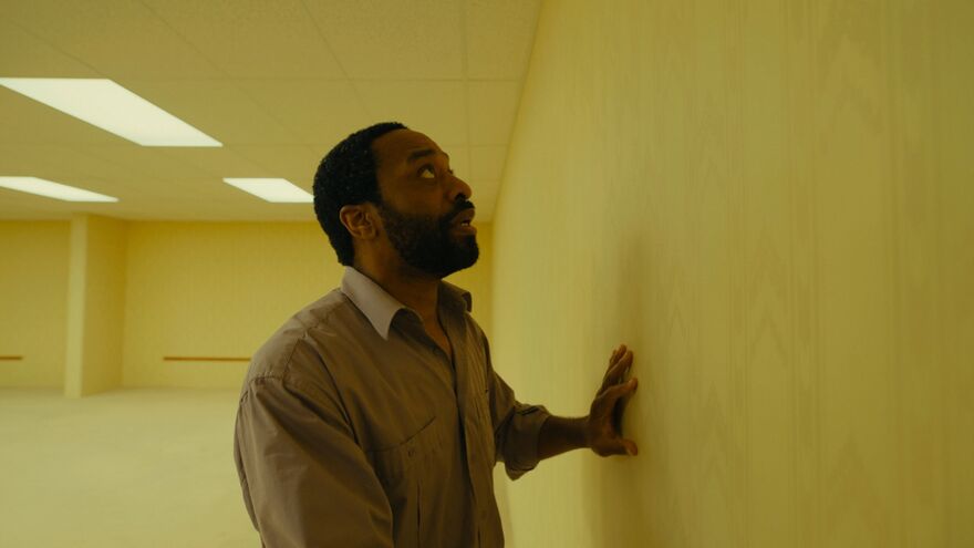A man looks in horror at a blank wall where a door has disappeared.