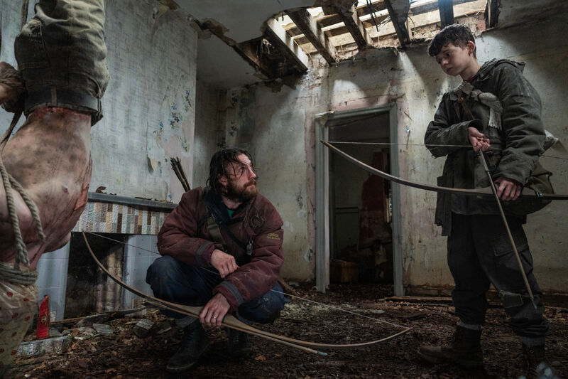A group of people hold crossbows in an abandoned house.