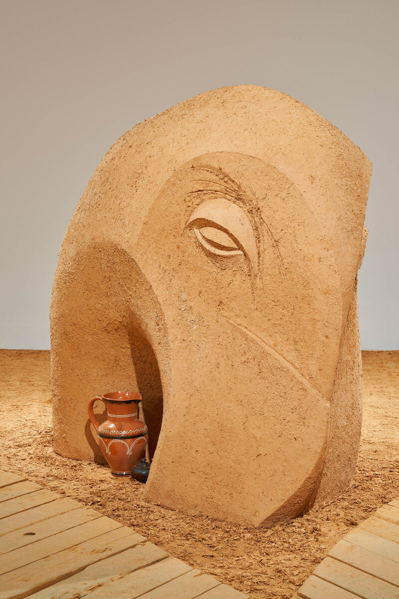 a clay sculpture of a figure with a large mouth and a pot inside it