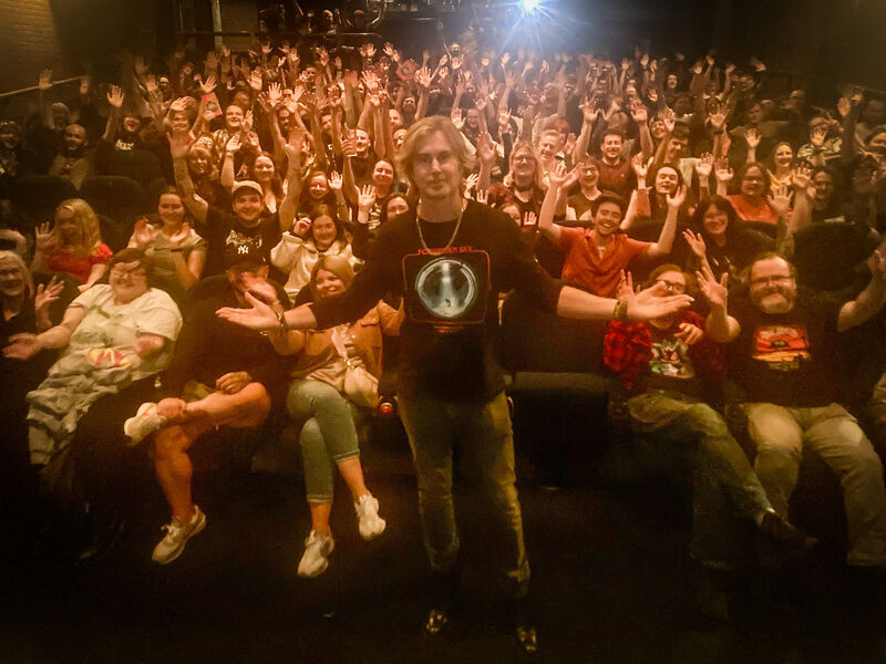 A happy busy cinema full of film fans with Greg Sestero at the front.