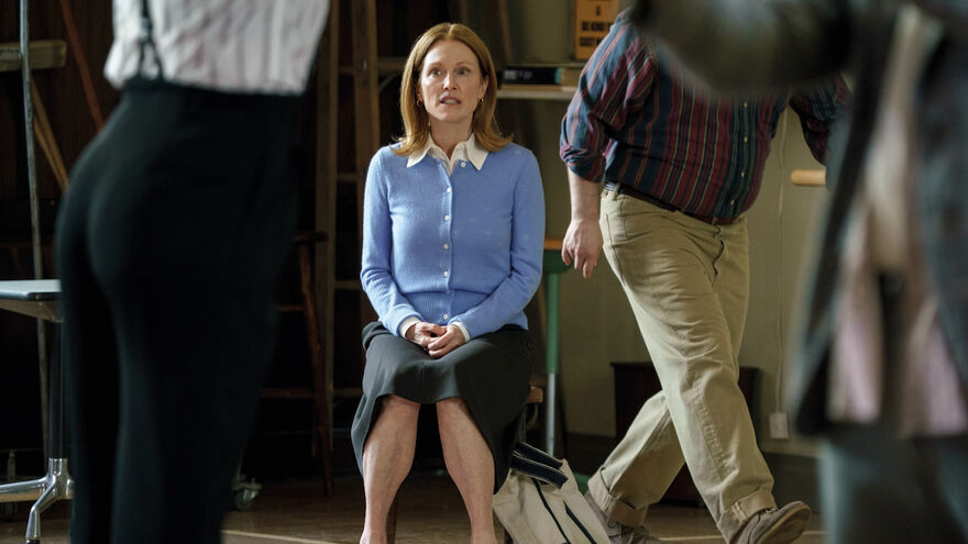 A nervous woman sits while people move hurriedly around her