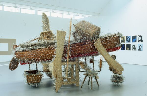 A fishing boat is covered in large, sharp metal hooks. There are pieces of wood attached to the fishing boat.