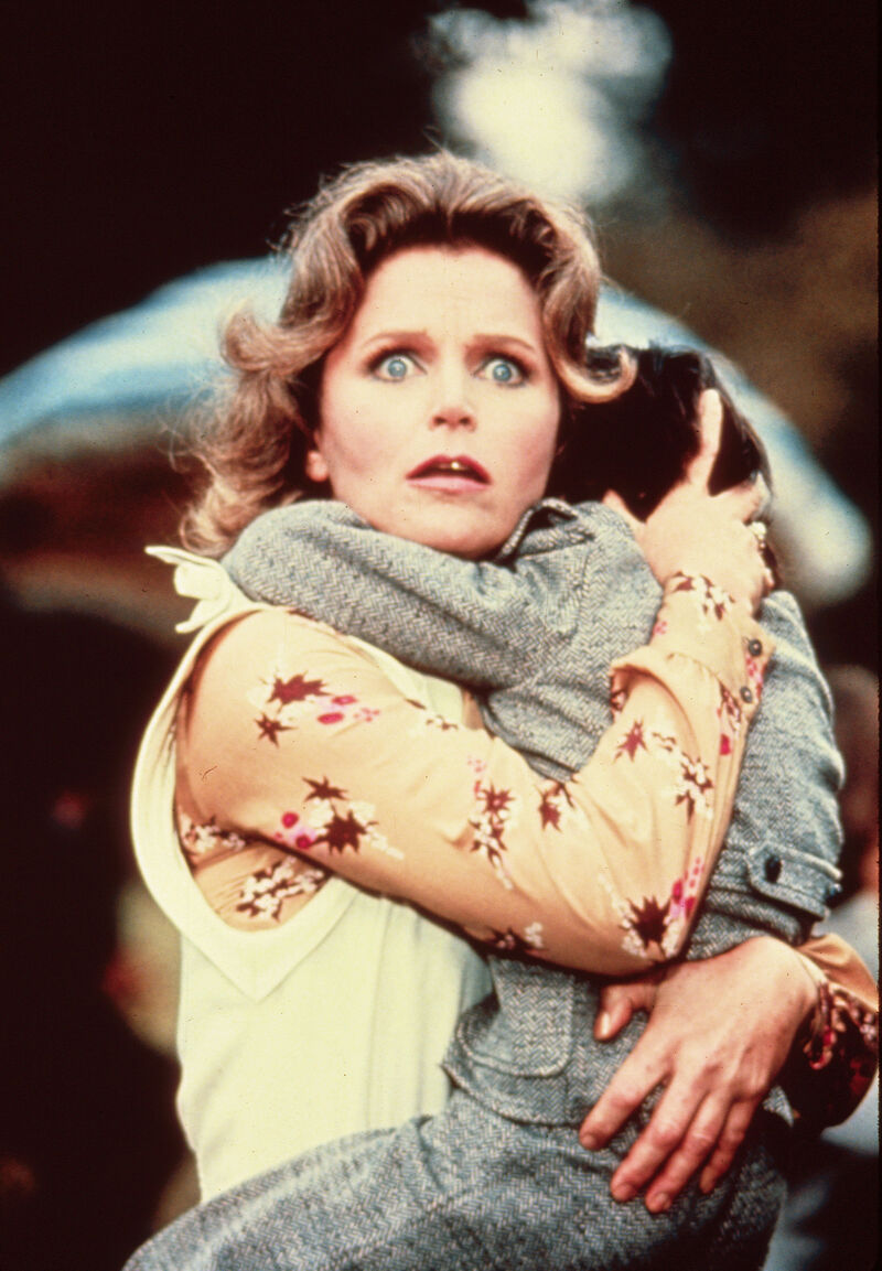 A woman holding a child and looking frightened