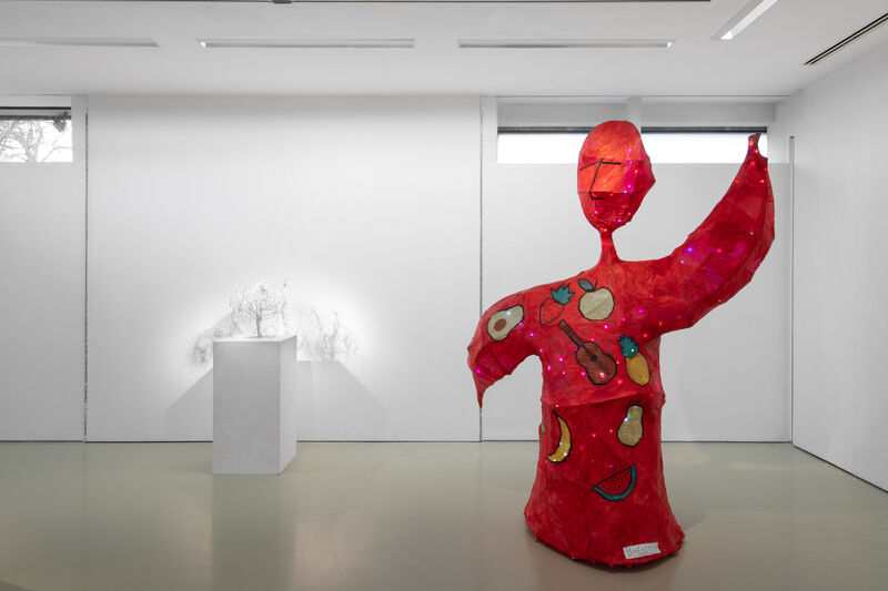Photo of a larfe sculpture of a red figure decorated with images of fruit and a guitar