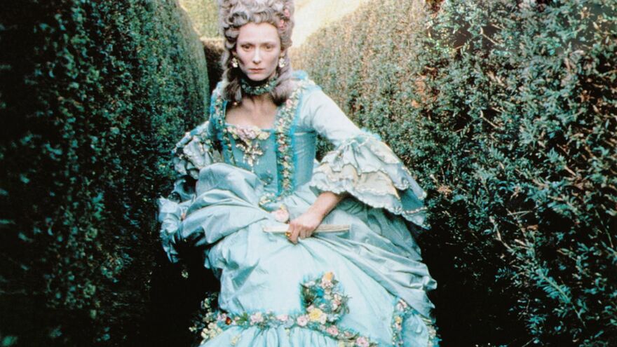 A still from the film 'Orlando' shows Tilda Swinton in 18th century clothing walking through a hedge maze.
