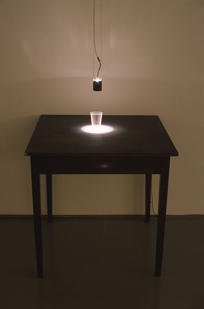 From The Eye of the Beholder - a white glass sits on a large black table.