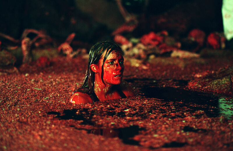 Woman emerging from an underground pool covered in red