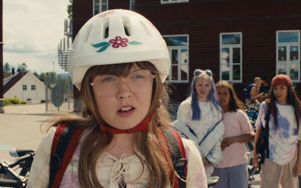 Girl wearing a cycle helmet and backpack in a school playground