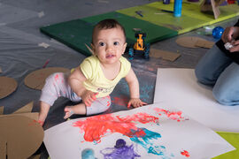 Child painting onto a piece of paper using their hands