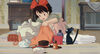 a young girl bundles clothes while watched by a black cat