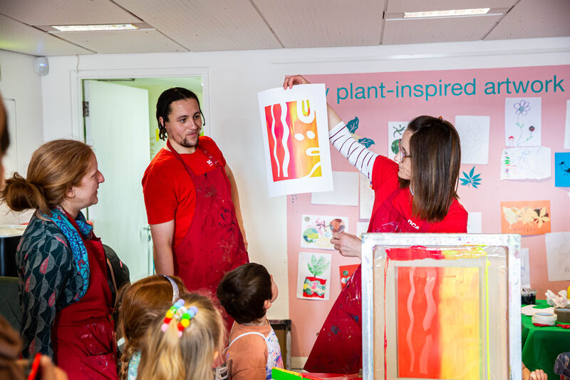 Two learning tutors showing a group of children the results of screen printing