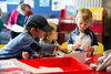 Three children at a table in createspace using art materials