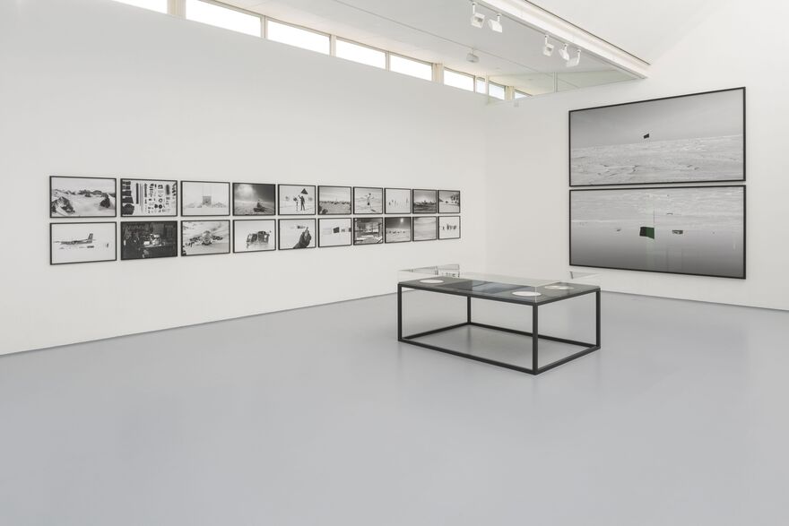 An image from Santiago Sierra's exhibition Black Flag shows black and white photography in black frames on white walls.