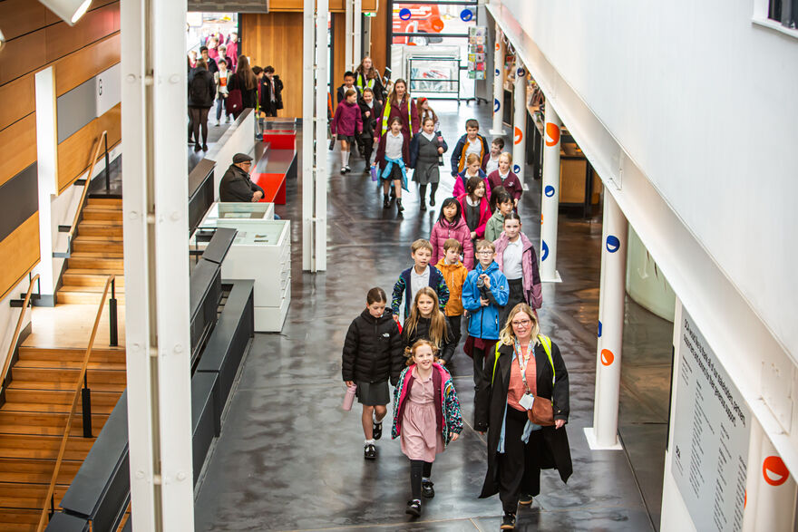A group of children and their teacher walking into DCA building.