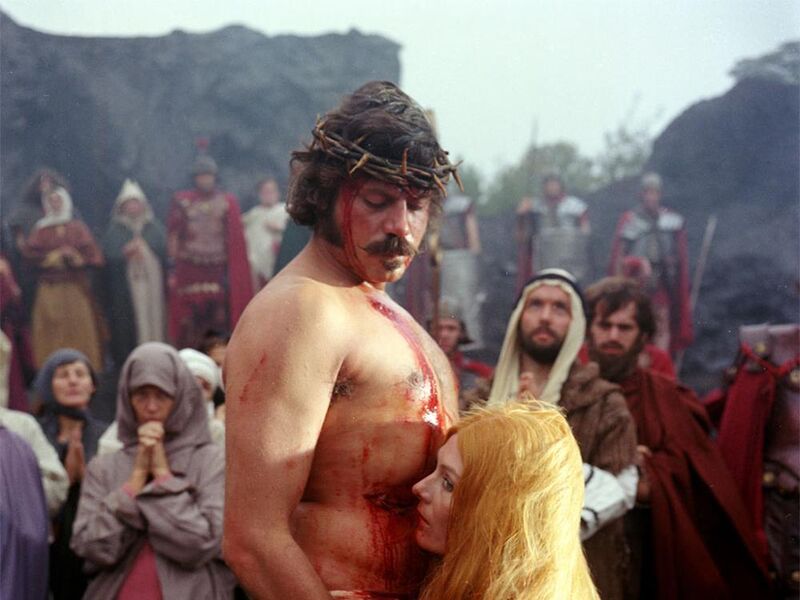 Man with thorns around his head bing held by a woman in front of a crowd