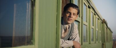 A man in 1930s clothing leans out of a train window