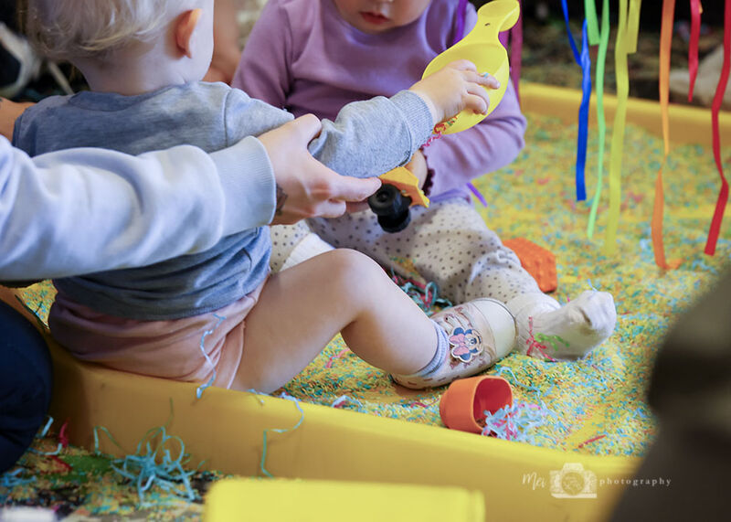 Two small children playing with colourful sand