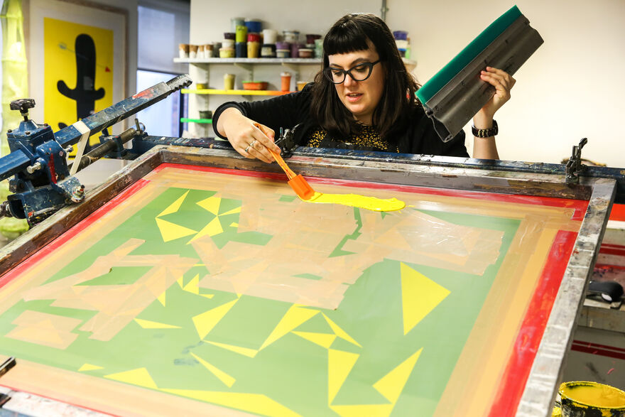 Person spreading yellow ink onto a screen