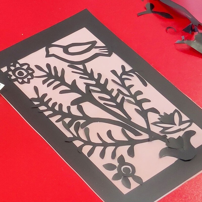 Collage with black paper featuring a bird in a tree and flowers